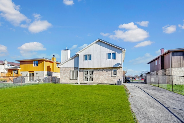 back of property with central air condition unit and a yard