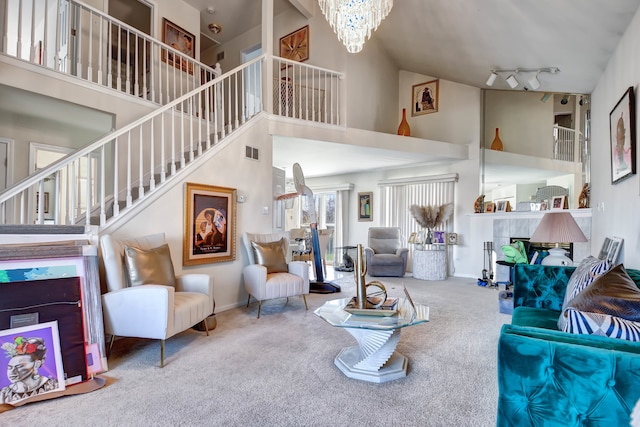 living room with carpet flooring, rail lighting, a notable chandelier, a fireplace, and a high ceiling