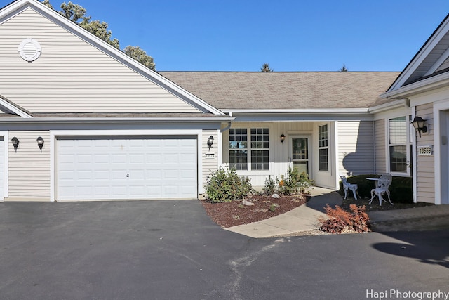 view of front of property with aphalt driveway, an attached garage, and a shingled roof