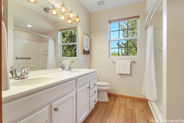 bathroom with visible vents, toilet, wood finished floors, and a sink