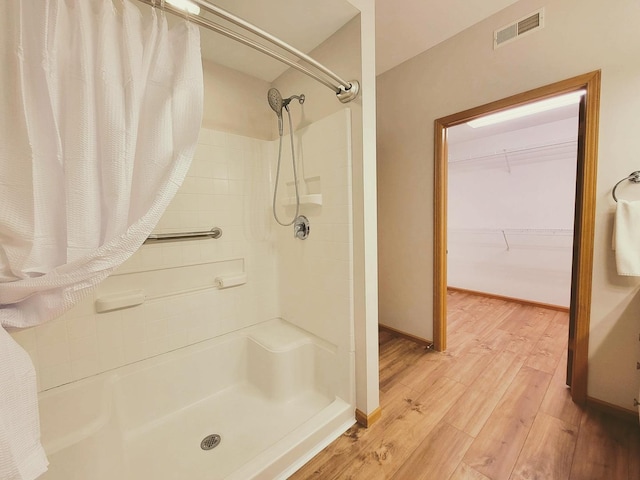 full bathroom featuring a shower with shower curtain, visible vents, baseboards, and wood finished floors