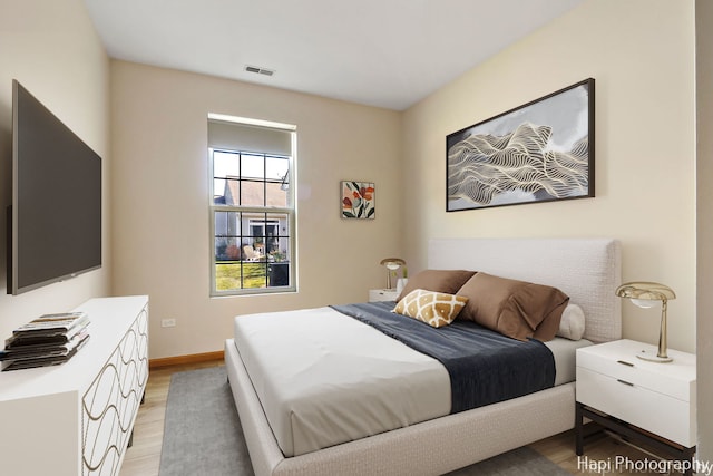 bedroom with visible vents, baseboards, and light wood finished floors