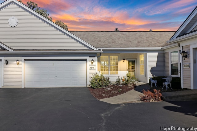 view of front of home with an attached garage, roof with shingles, and driveway