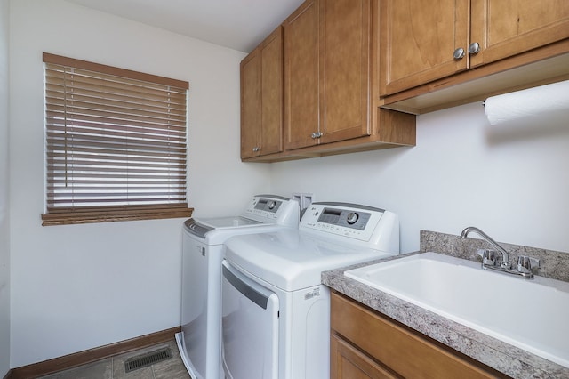 clothes washing area with washer and dryer, cabinets, and sink