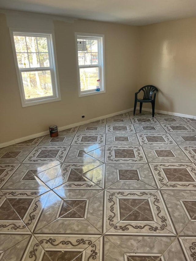 spare room with baseboards, a healthy amount of sunlight, and tile patterned flooring