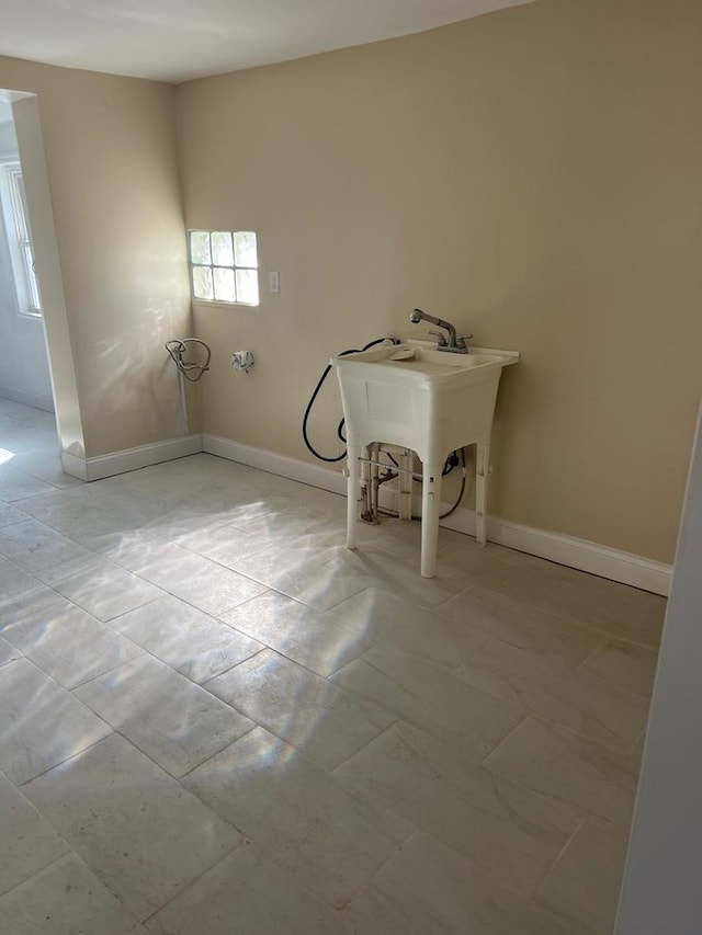 washroom featuring baseboards and a sink