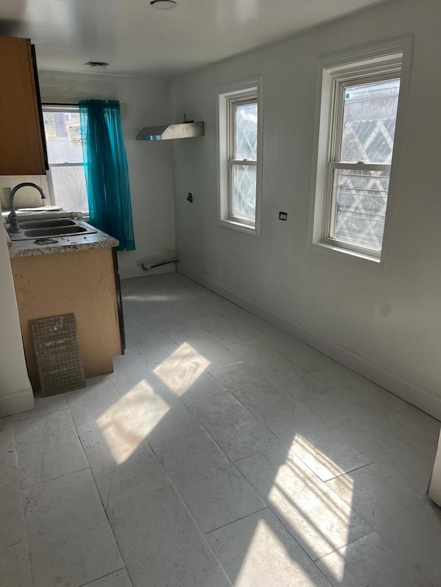 kitchen with a sink, baseboards, and a healthy amount of sunlight