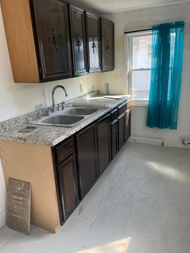 kitchen with dark brown cabinetry, light countertops, and a sink