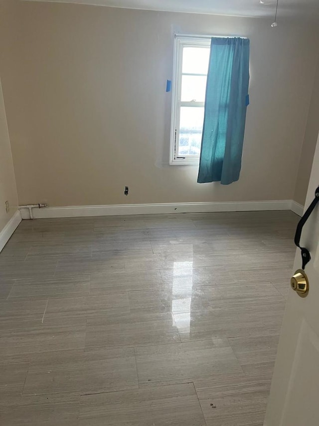 unfurnished room with baseboards