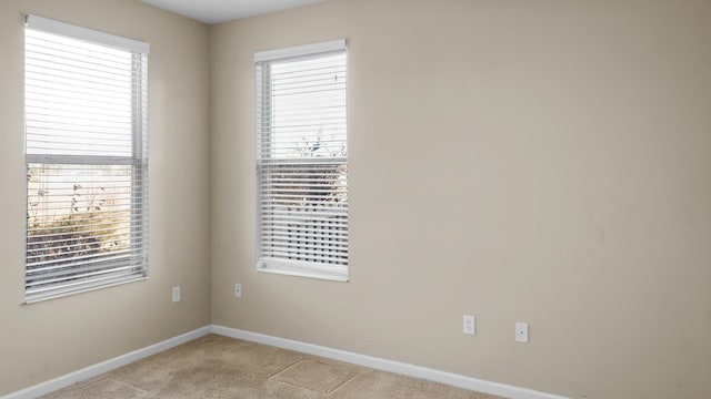 unfurnished room with light colored carpet and a wealth of natural light