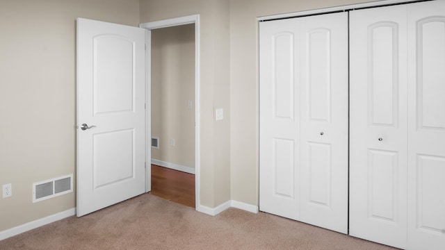 unfurnished bedroom with light carpet and a closet