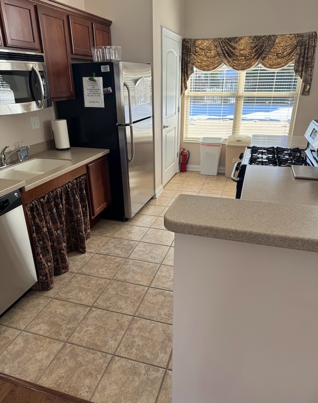 kitchen featuring light tile patterned floors, stainless steel appliances, and sink