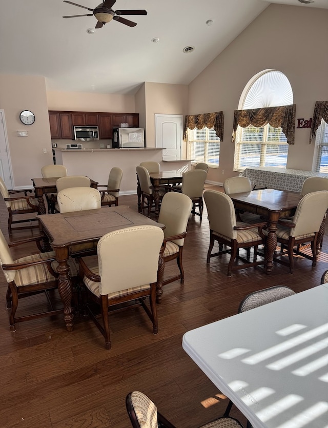 dining room with ceiling fan, dark wood-type flooring, and high vaulted ceiling