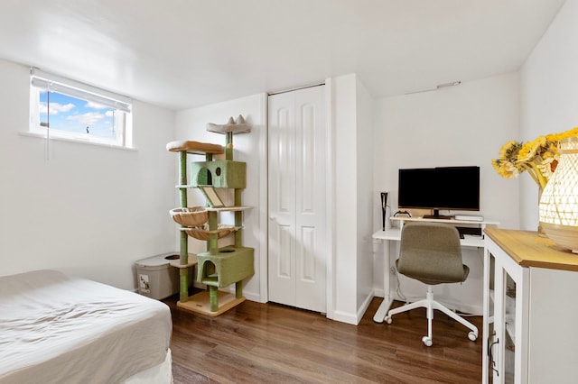 bedroom with dark hardwood / wood-style floors and a closet