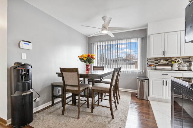 dining space with ceiling fan, wood-type flooring, and vaulted ceiling