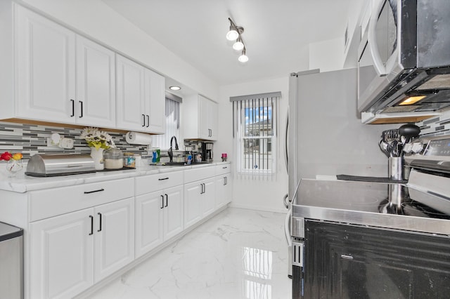 kitchen featuring backsplash, white cabinetry, sink, and appliances with stainless steel finishes