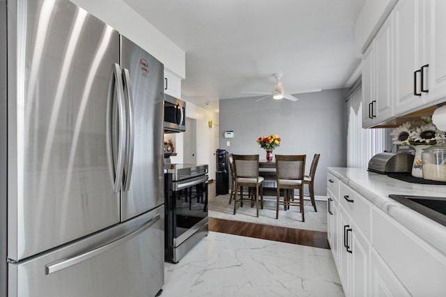 kitchen with white cabinets, stainless steel appliances, ceiling fan, and light hardwood / wood-style floors