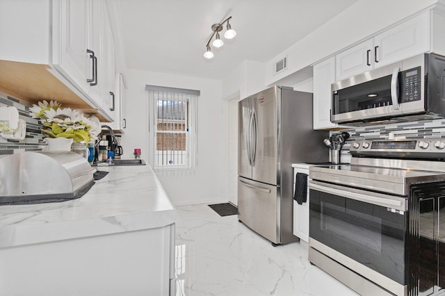 kitchen featuring decorative backsplash, light stone counters, stainless steel appliances, sink, and white cabinetry