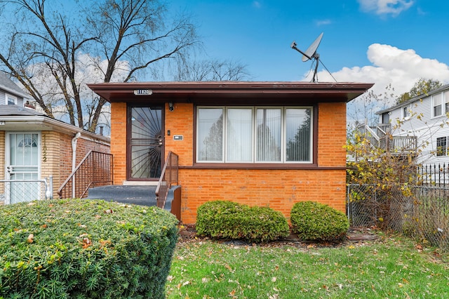 view of front of house featuring brick siding and fence