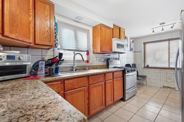 kitchen with light stone countertops, gas range, plenty of natural light, and light tile patterned flooring