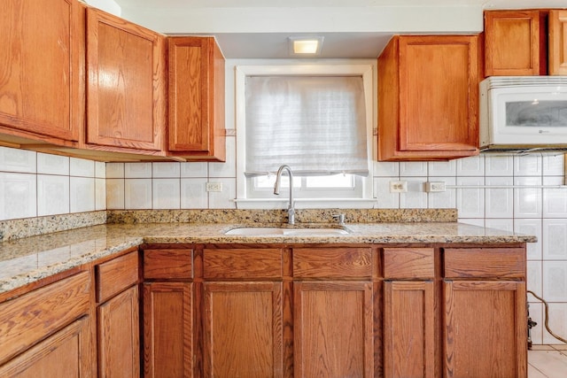 kitchen with white microwave, brown cabinets, and a sink