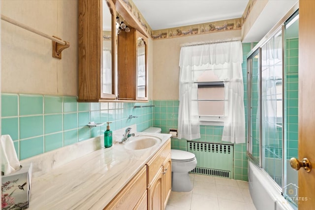 full bathroom featuring radiator heating unit, tile patterned flooring, toilet, vanity, and tile walls