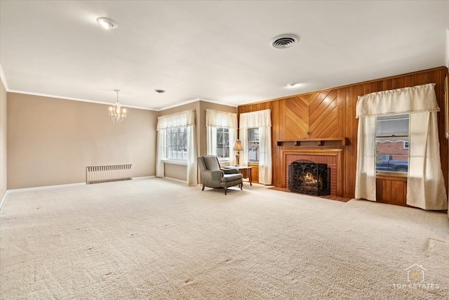 unfurnished living room featuring a fireplace, radiator heating unit, wooden walls, and crown molding