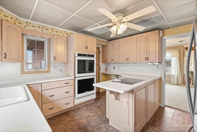 kitchen featuring ceiling fan, white double oven, sink, black electric cooktop, and light brown cabinetry