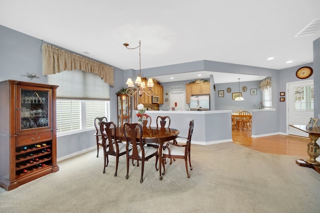 carpeted dining area with a chandelier