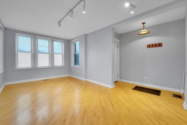 spare room featuring track lighting and light hardwood / wood-style flooring