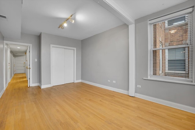 unfurnished bedroom with a closet, light hardwood / wood-style floors, and multiple windows