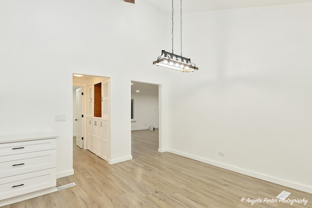 unfurnished room featuring a high ceiling and light wood-type flooring