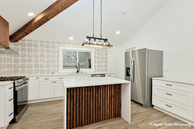 kitchen with sink, vaulted ceiling with beams, appliances with stainless steel finishes, decorative light fixtures, and a kitchen island