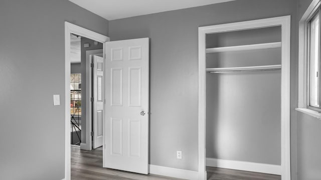 unfurnished bedroom featuring multiple windows, a closet, and dark hardwood / wood-style flooring