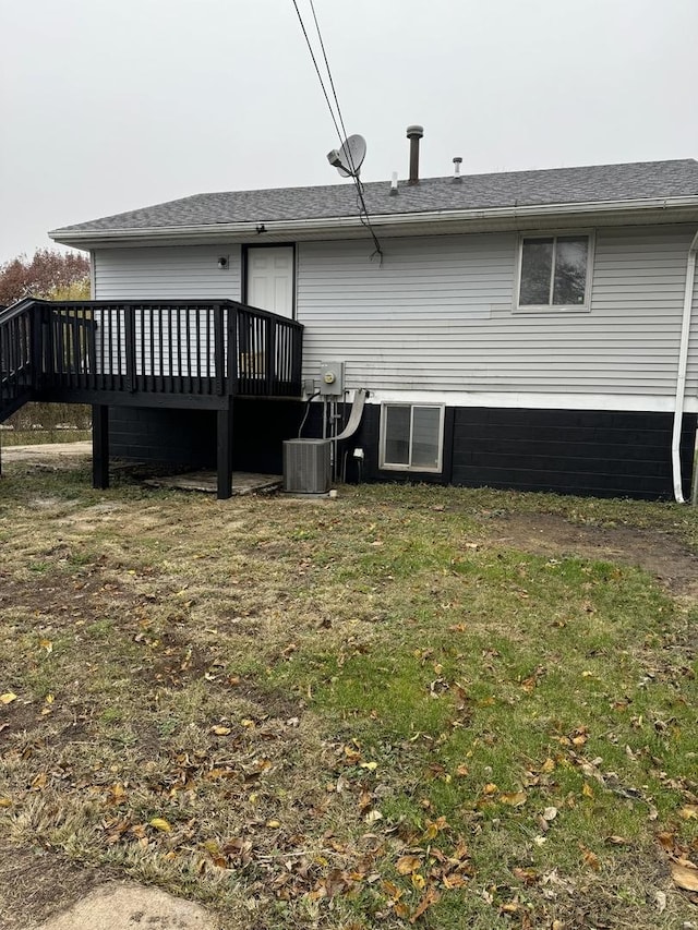 back of house with central AC unit, a lawn, and a wooden deck