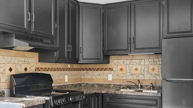 kitchen with tasteful backsplash, stainless steel refrigerator, black range oven, and sink