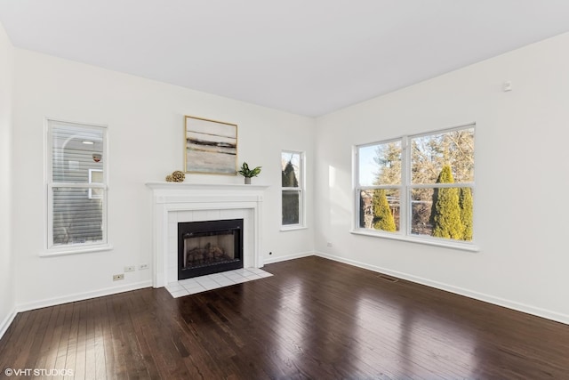 unfurnished living room with hardwood / wood-style flooring and a tiled fireplace