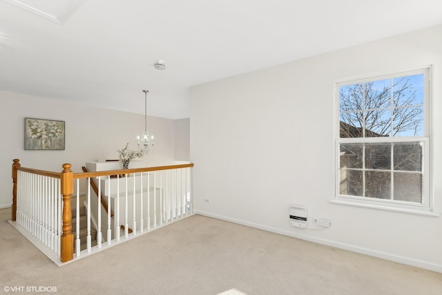 spare room featuring light colored carpet and an inviting chandelier