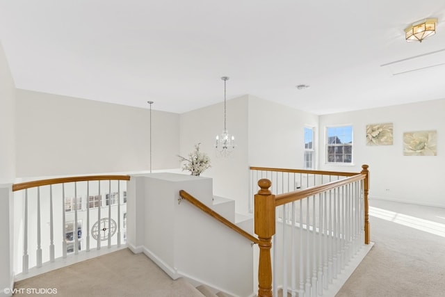 hall featuring light colored carpet and an inviting chandelier