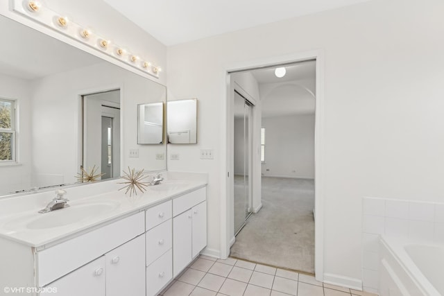 bathroom featuring tile patterned flooring, vanity, and a washtub