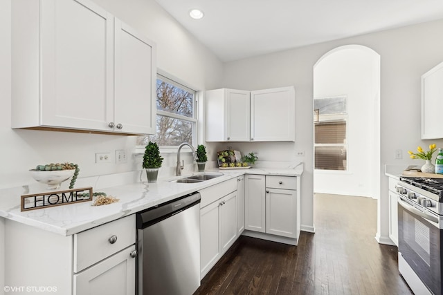 kitchen with light stone counters, stainless steel appliances, dark wood-type flooring, sink, and white cabinets