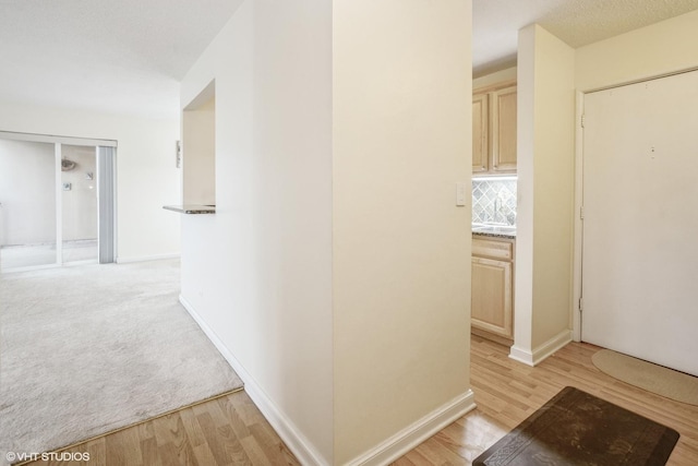 hall with a textured ceiling and light hardwood / wood-style floors