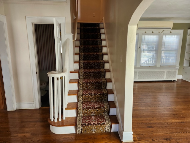 stairs with a wall mounted air conditioner, radiator heating unit, ornamental molding, and hardwood / wood-style floors