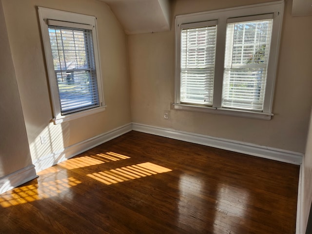 unfurnished room with a wealth of natural light, dark wood-type flooring, and vaulted ceiling