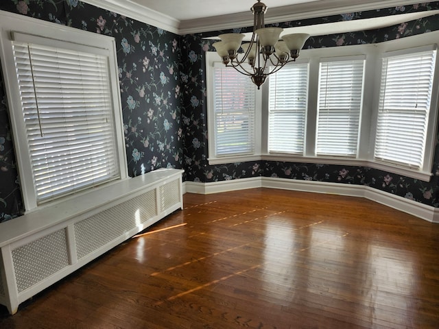 unfurnished dining area featuring dark hardwood / wood-style flooring, crown molding, radiator heating unit, and a chandelier