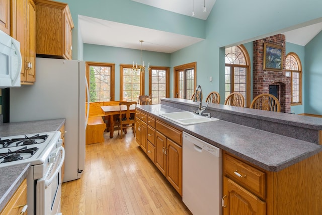 kitchen featuring white appliances, sink, decorative light fixtures, a fireplace, and lofted ceiling