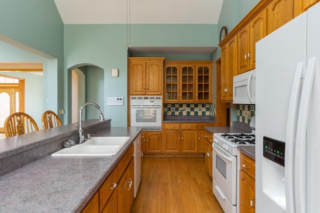 kitchen with white appliances, backsplash, light hardwood / wood-style floors, and sink