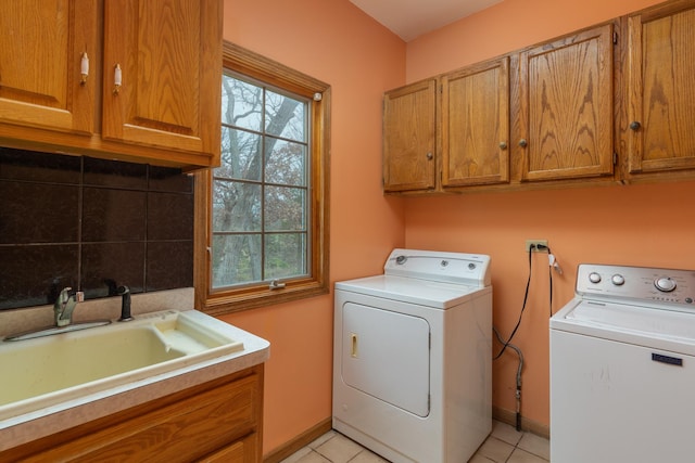 clothes washing area featuring cabinets, light tile patterned floors, washing machine and dryer, and sink