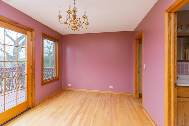 spare room featuring a notable chandelier and light hardwood / wood-style flooring