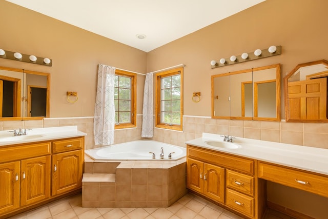 bathroom featuring tile patterned floors, a relaxing tiled tub, tile walls, and vanity